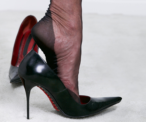 Ein Frauenfuß im Nylonstrumpf steckt in einem Stöckelschuh. Der Anblick ist sehr erregend.